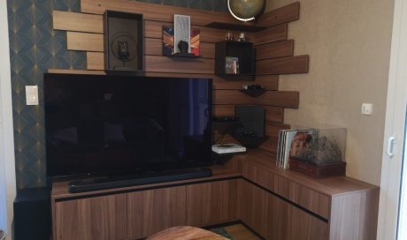 Meuble TV d'angle avec tiroirs et abattants en partie basse et panneau mural avec étagères réglables.